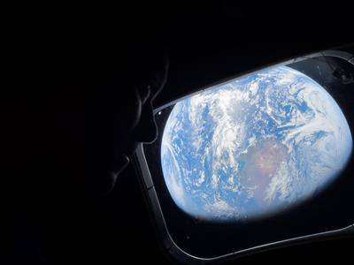 Astronaut silhouette viewing Earth through the window